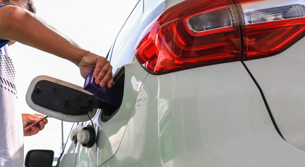 Fuel Additive | Person screwing on a gas cap to a white car